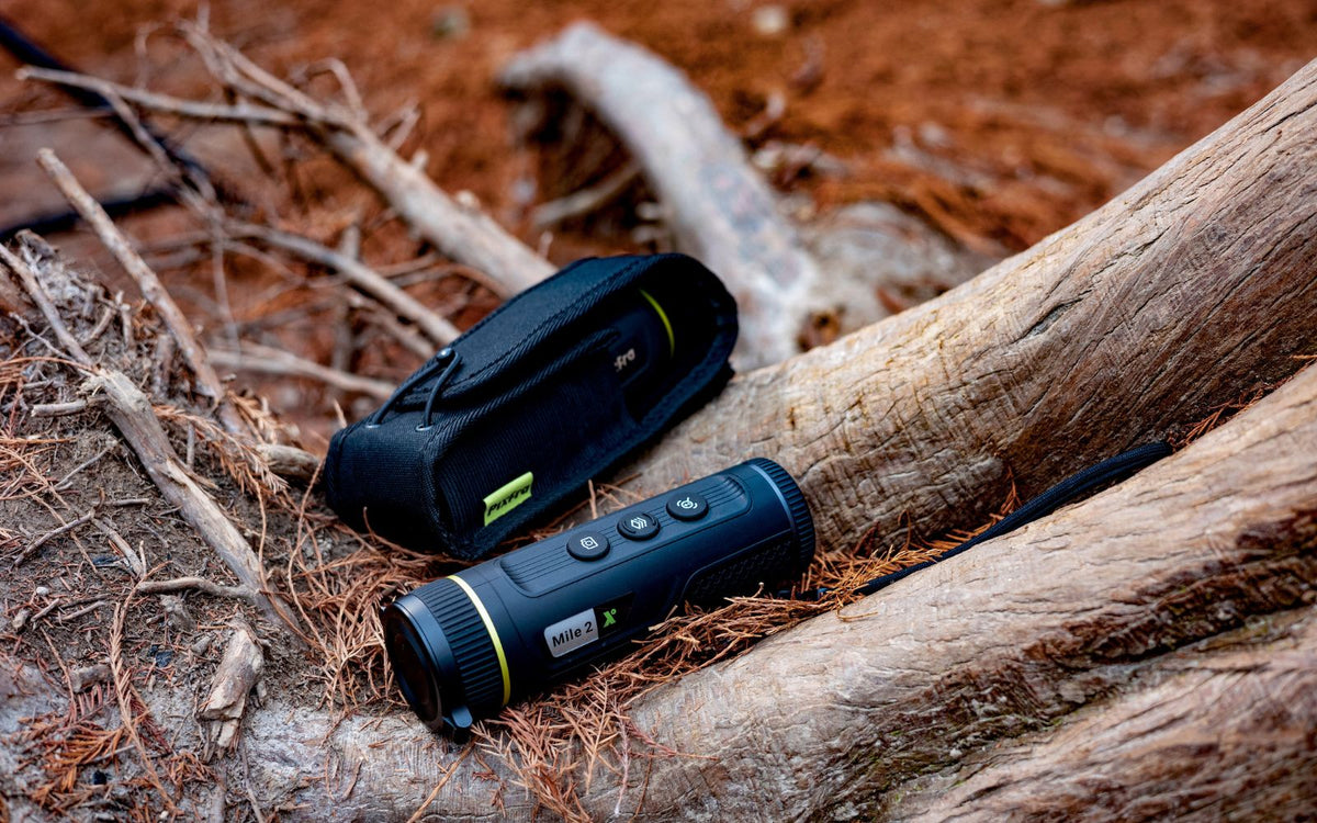 Monoculaire thermique Pixfra Mile 2 M207 avec étui de transport présenté sur un sol forestier pour les activités outdoor