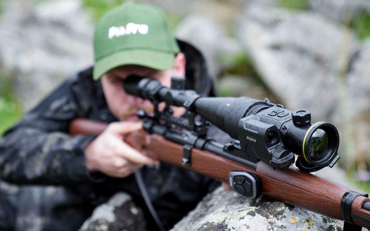 Chasseur en visée avec la caméra thermique clip-on Pixfra Taurus montée devant sa lunette de jour, télémètre laser et télécommande sur la crosse